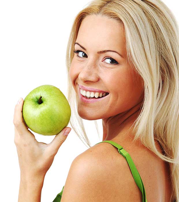 Frau mit gesunden Zähnen und grünem Apfel